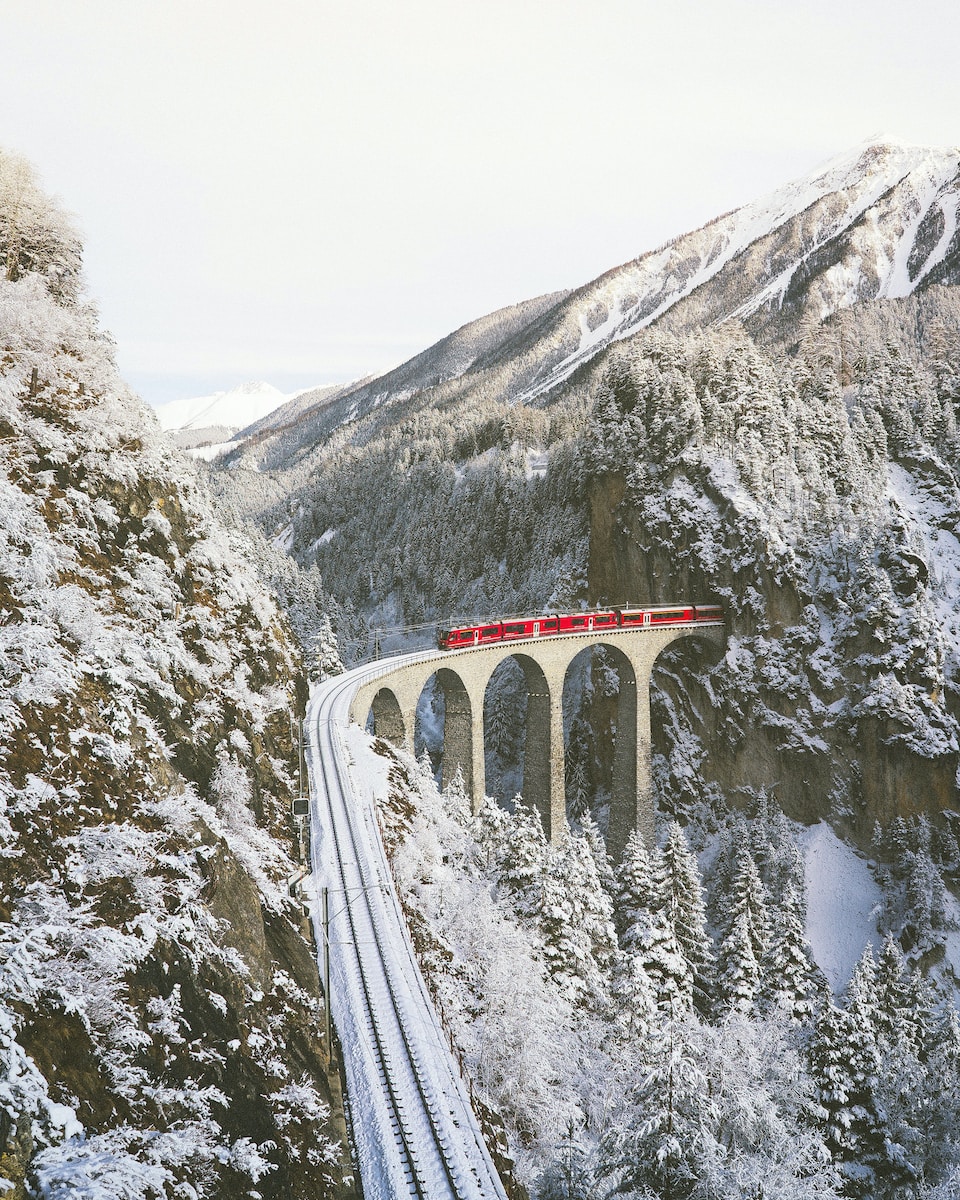 Photo by Johannes Hofmann approaching red train across mountains